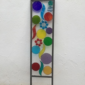 以下が含まれることがあります： さまざまな形とサイズのカラフルなステンドグラスのガーデンステーク。ステークは金属製で、赤、オレンジ、黄色、緑、青、紫など、さまざまな色を使用しています。