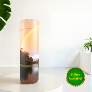 May include: A cylindrical container featuring a landscape with a rainbow over a river and trees. The container is beige with a dark brown base. A green sticker displays the text "5 Sizes Available!"