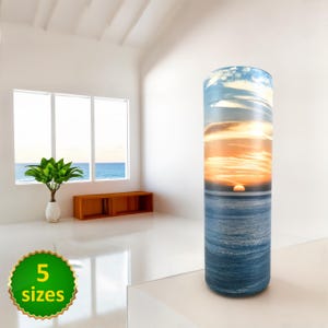 May include: A cylindrical cremation urn featuring a sunset over the ocean scene. The urn is made from a durable material and is available in five sizes.