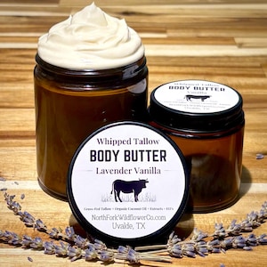 May include: Two amber glass jars of whipped tallow body butter with black lids. One jar is open, showing white whipped cream, while the other is closed with a label reading Whipped Tallow BODY BUTTER Lavender Vanilla and NorthForkWildflowerCo.com.