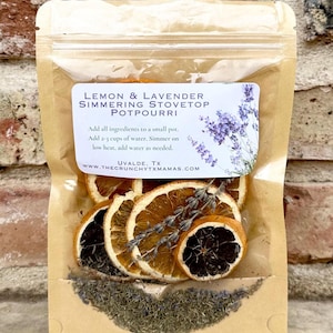 May include: A clear, resealable bag filled with dried orange slices, lavender sprigs, and herbs. The bag has a label that reads "Lemon & Lavender Simmering Stovetop Potpourri." The potpourri is designed to be simmered on the stovetop.