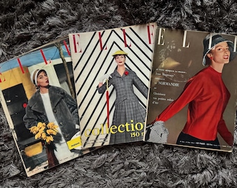 May include: Three vintage copies of ELLE magazine featuring fashion models on the covers. The covers are red, white, and black with the word "ELLE" printed in large letters. The magazines are from the 1950s and feature articles about fashion, beauty, and culture.