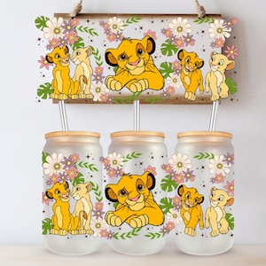 Peut inclure: Trois verres en verre transparent avec couvercles et pailles. Chaque verre présente une image différente de Simba et Nala du Roi Lion, entourés de fleurs. Les verres sont parfaits pour déguster vos boissons préférées.