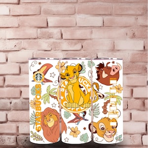 Peut inclure: Trois gobelets blancs sur le thème de la jungle avec Simba, Mufasa et Pumbaa du film d'animation de Disney Le Roi Lion. Les gobelets ont un logo Starbucks et le texte "Starbucks Coffee".