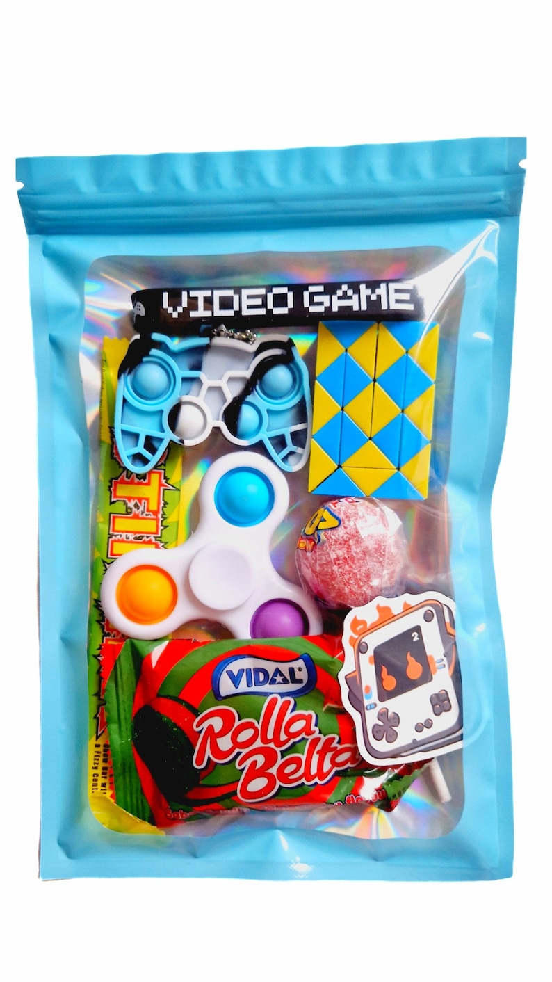 May include: A blue zippered pouch with a clear window showing a variety of small toys and sweets. The toys include a blue and white fidget toy shaped like a video game controller, a white fidget spinner, a yellow and blue puzzle, and a red lollipop. The sweets are a red and green wrapped candy bar with the text "Vidal Rolla Bella" on it. There is also a sticker of a video game console with flames on it.