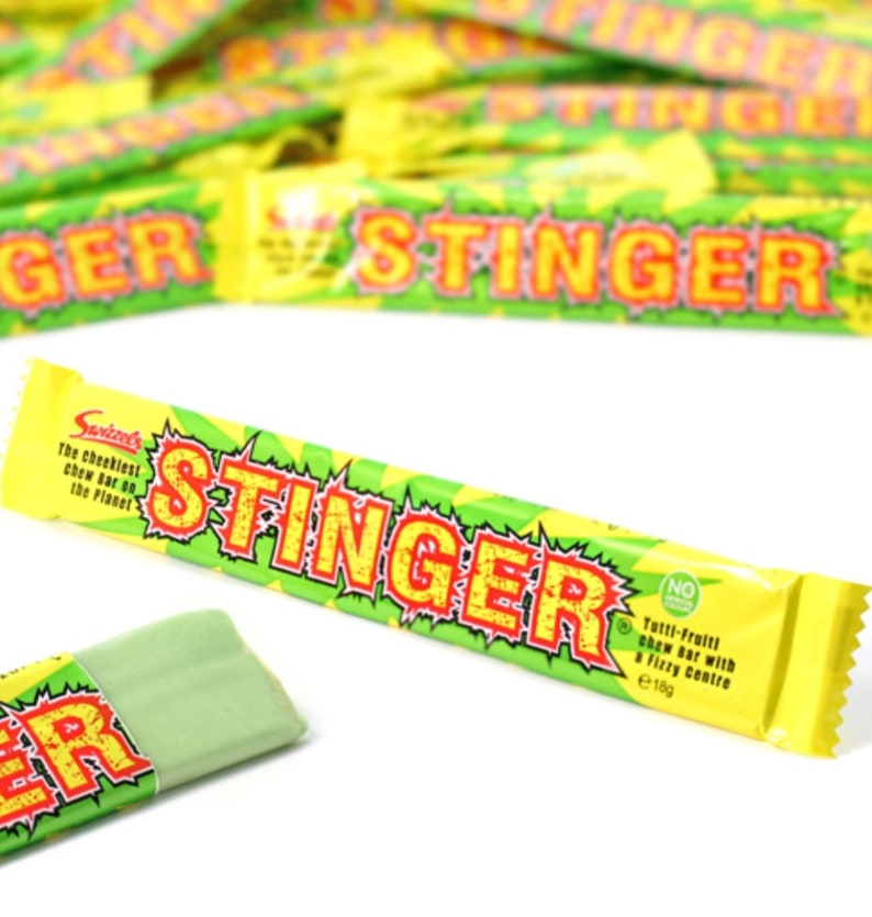 May include: A yellow and green candy bar wrapper with the text "STINGER" in red and yellow letters. The wrapper says "The cheekiest chew bar on the planet" and "Tutti-fruiti chew bar with a fizzy centre".