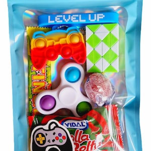 May include: A blue zippered pouch with a clear window showing a variety of small toys and sweets. The pouch has the words "LEVEL UP" printed on it. The toys include a rainbow coloured fidget toy shaped like a game controller, a white fidget spinner, a green puzzle cube, and a red lollipop. The sweets are a red and green packet of watermelon flavoured gummies.
