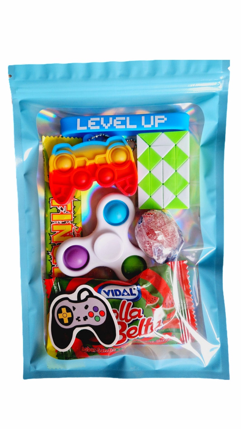 May include: A blue zippered pouch with a clear window showing a variety of small toys and sweets. The pouch has the words "LEVEL UP" printed on it. The toys include a rainbow coloured fidget toy shaped like a game controller, a white fidget spinner, a green puzzle cube, and a red lollipop. The sweets are a red and green packet of watermelon flavoured gummies.