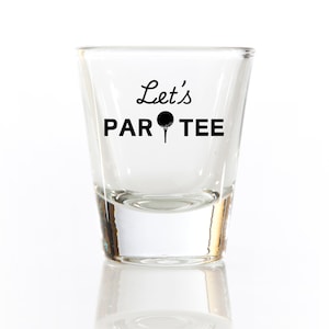 May include: A clear glass shot glass with the text "Let's Par Tee" and a golf ball graphic.