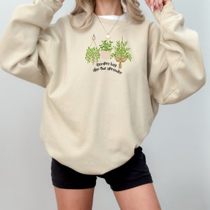 May include: A beige sweatshirt with a graphic of hanging plants and the text "Siempre hay algo que aprender".