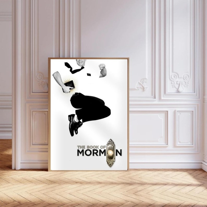 Op de afbeelding: Een zwart-wit poster met een man die in de lucht springt terwijl hij een boek vasthoudt. De poster heeft de tekst "The Book of Mormon" in zwarte letters.