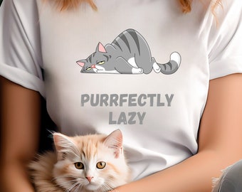 May include: A white t-shirt featuring a cartoon grey cat lying down with the text "Purrfectly Lazy". A person is wearing the shirt and holding a light brown cat.