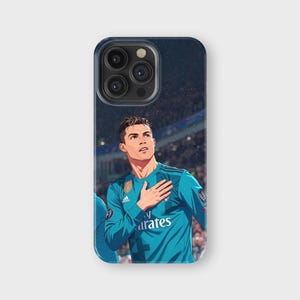 May include: A phone case featuring an illustration of a soccer player in a teal jersey with the Emirates logo. The player is depicted with his hand over his heart, set against a stadium background.