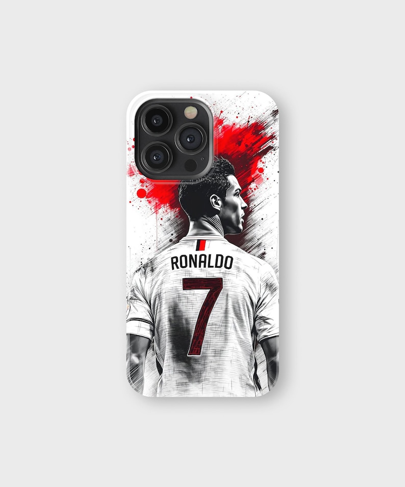 May include: A white phone case featuring a stylized image of a soccer player with the name "RONALDO" and the number "7" on the back of his jersey. The design includes red paint splatter accents.