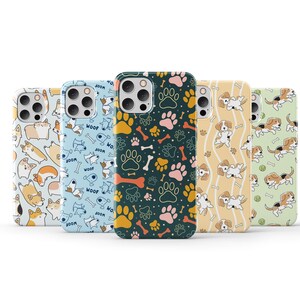 Op de afbeelding: Vijf verschillende telefoonhoesjes met verschillende hondenthema's. De hoesjes zijn allemaal wit met een zwarte camera-uitsparing. De patronen omvatten voetafdrukken, botten en honden.