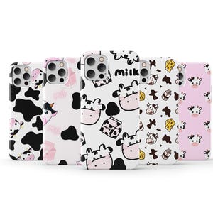 Puede incluir: Cinco fundas para teléfono diferentes con un tema de vaca y leche. Las fundas son blancas con detalles en negro y rosa. Las fundas presentan una variedad de diseños, incluyendo vacas, cartones de leche y la palabra "leche".
