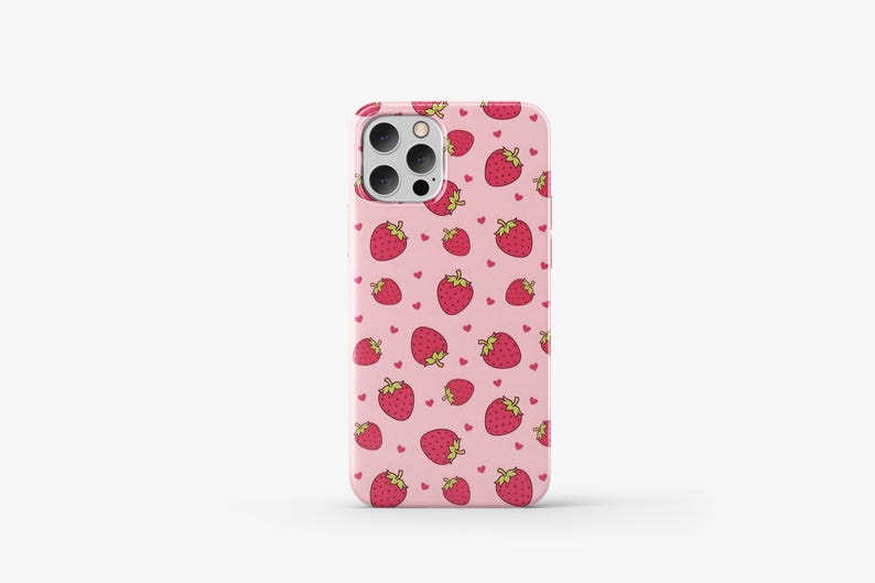 May include: A pink phone case with a pattern of red strawberries and white hearts.