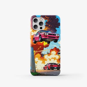 May include: A phone case with a colorful comic book style design featuring a pink car flying through the air with explosions and smoke. There is a second red car driving on the road below.
