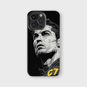 May include: Black phone case featuring a stylized portrait of a soccer player. The portrait is in black and white with yellow accents, including the number "C7" on the jersey. The phone case has a glossy finish.