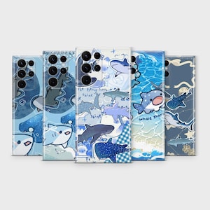 Può includere: Una collezione di custodie blu per telefoni con disegni di squali. Le custodie presentano squali dei cartoni animati, onde oceaniche e il testo "whale shark". Le custodie hanno una finitura lucida e sono esposte su uno sfondo chiaro.