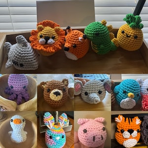 May include: A selection of crocheted animal toys in various colours. The collection includes a shark, lion, fox, dinosaur, and pineapple. Other animals include an octopus, bear, elephant, bird, bunny, pig, and tiger. Each toy is handmade with detailed features.