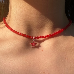 May include: A red beaded choker necklace with a red starfish charm.