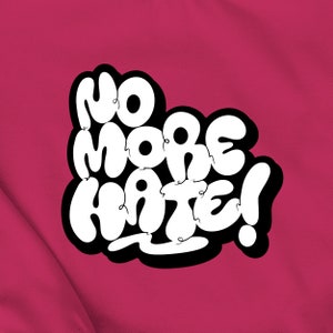 Könnte beinhalten: Weißer Text auf rosa Hintergrund, der "No More Hate!" in einer blasenartigen Schriftart lautet.
