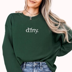 May include: A dark green sweatshirt with a white graphic of a martini glass and the word "dirty."