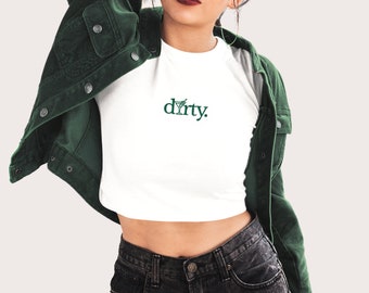 Puede incluir: Camiseta blanca recortada con un gráfico de copa de martini verde y el texto "dirty."