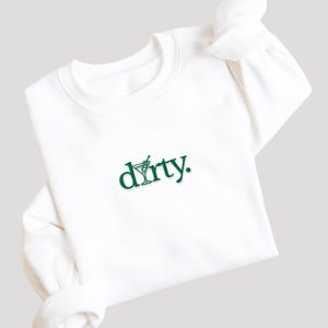 May include: White sweatshirt with a green graphic of a martini glass and the word "dirty."