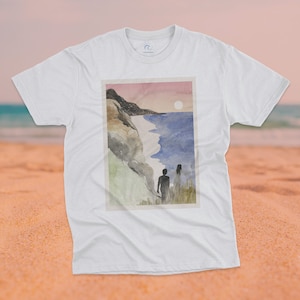 May include: White t-shirt with a watercolor illustration of a couple standing on a cliff overlooking a beach with a sunset in the background.