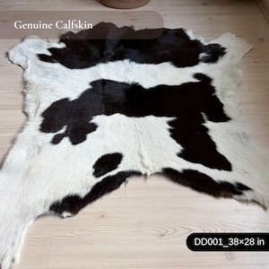 Könnte beinhalten: Echter Kalbsfellteppich mit einem schwarz-weißen Muster. Der Teppich misst 96 x 71 cm. Der Text "Genuine Calfskin" ist im Bild sichtbar.