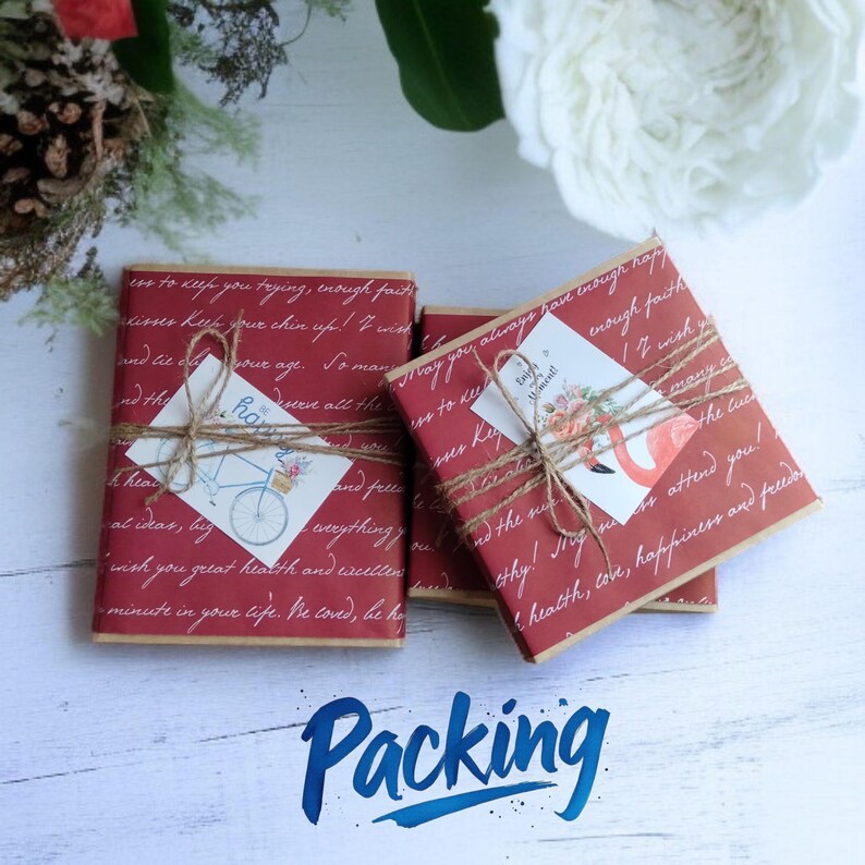 May include: Three gift boxes wrapped in red paper with handwritten text and tied with twine. Each box has a small card attached with a bicycle or flamingo illustration. The word "Packing" is written in blue script at the bottom.