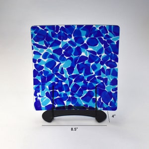 May include: A blue and white glass serving tray with a stand. The tray is 8.5 inches wide and 4 inches tall. The tray has a mosaic pattern of blue and white glass pieces.