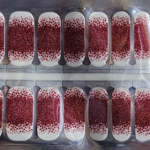 May include: A pack of red glitter nail polish strips. The strips are arranged in two rows of ten, with each strip being a different size to fit different fingernails.