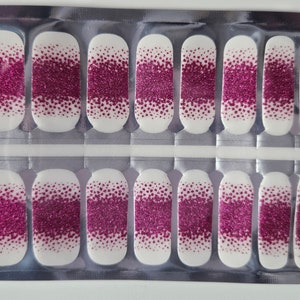 May include: A sheet of pink glitter nail polish wraps in a clear plastic package. The wraps are designed to be applied to fingernails.