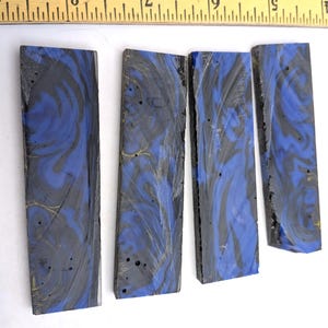 May include: Four rectangular blocks of resin material featuring a marbled pattern of deep blue, black, and subtle gold swirls. A yellow wooden ruler is positioned at the top, showing the blocks measure approximately 5 inches in length.