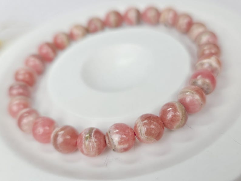 May include: A pink and white gemstone bracelet with round beads. The bracelet is made of natural stones and has a delicate, feminine look.