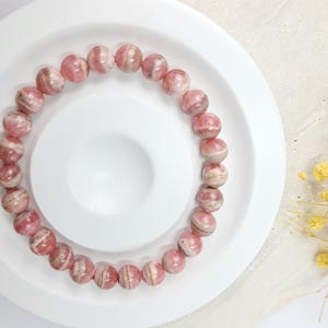 May include: A pink and white striped gemstone bracelet with round beads.
