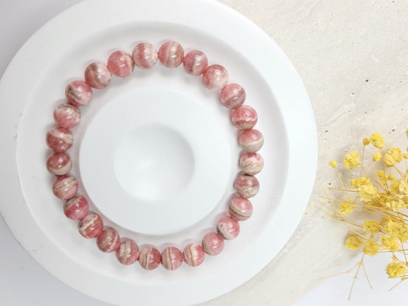 May include: A pink and white striped gemstone bracelet with round beads.