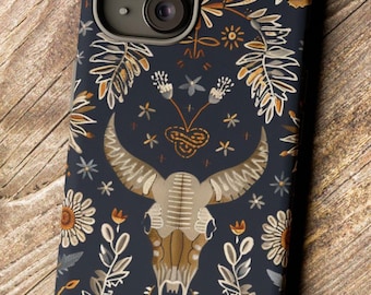May include: A dark blue phone case with a floral pattern and a skull design. The skull is surrounded by leaves and flowers in shades of orange, yellow, and white.