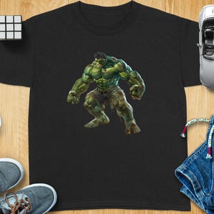 Puede incluir: Camiseta negra con un gran gráfico de Hulk, un superhéroe de piel verde, en una pose dinámica. La imagen muestra una musculatura detallada y pantalones rasgados. La camiseta está rodeada de accesorios de juguete, incluyendo gafas de sol, un coche de juguete y un cubo de Rubik.