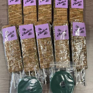 May include: A collection of ten moss poles for plant support, each wrapped in natural fibers and secured with twine. Each pole has a purple label that reads "Plantera". Two green plant support discs are also included.