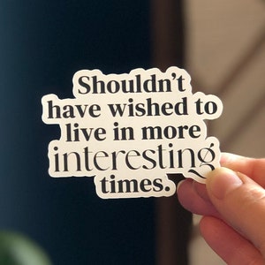 May include: White sticker with black text that reads "Shouldn't have wished to live in more interesting times."