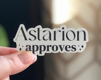 Peut inclure: Un autocollant transparent avec le texte "Astarion approves" en lettres noires.