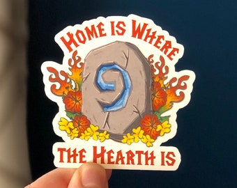 Peut inclure: Un autocollant avec un motif de foyer en pierre et le texte "Home is where the hearth is". La pierre a un numéro neuf bleu dessus et est entourée de flammes orange et de fleurs jaunes.
