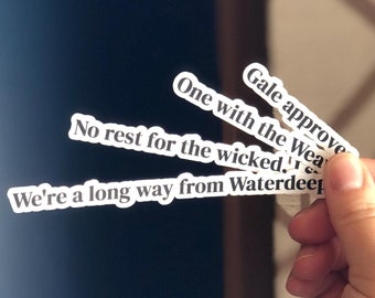 Peut inclure: Une main tenant cinq autocollants blancs avec du texte noir. Le texte sur les autocollants est : "Gale approve", "One with the Wea", "No rest for the wicked", "We're a long way from Waterdeep".