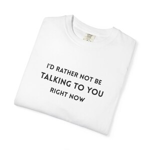 Peut inclure: Un t-shirt blanc à col rond avec le texte noir "I'D RATHER NOT BE TALKING TO YOU RIGHT NOW" imprimé dans une police sans empattement sur la poitrine. Le vêtement présente une étiquette de col intérieure visible avec des informations de taille.