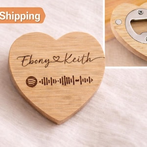 May include: Heart-shaped wooden bottle opener with a Spotify code and the names "Ebony & Keith" engraved on it. The opener has a silver metal opener and a magnet on the back. The wood has a light brown colour.