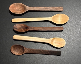 Könnte beinhalten: Fünf Holzlöffel, zwei dunkelbraun und drei hellbraun, in einer Reihe auf einer schwarzen Oberfläche angeordnet.